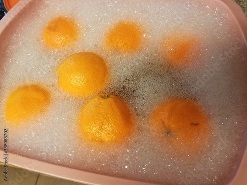 oranges in soapy water in pink plastic tub