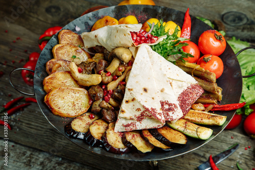  Restaurant dish on a wooden background. Azerbaijani saj with meat and vegetables. photo