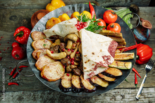  Restaurant dish on a wooden background. Azerbaijani saj with meat and vegetables.