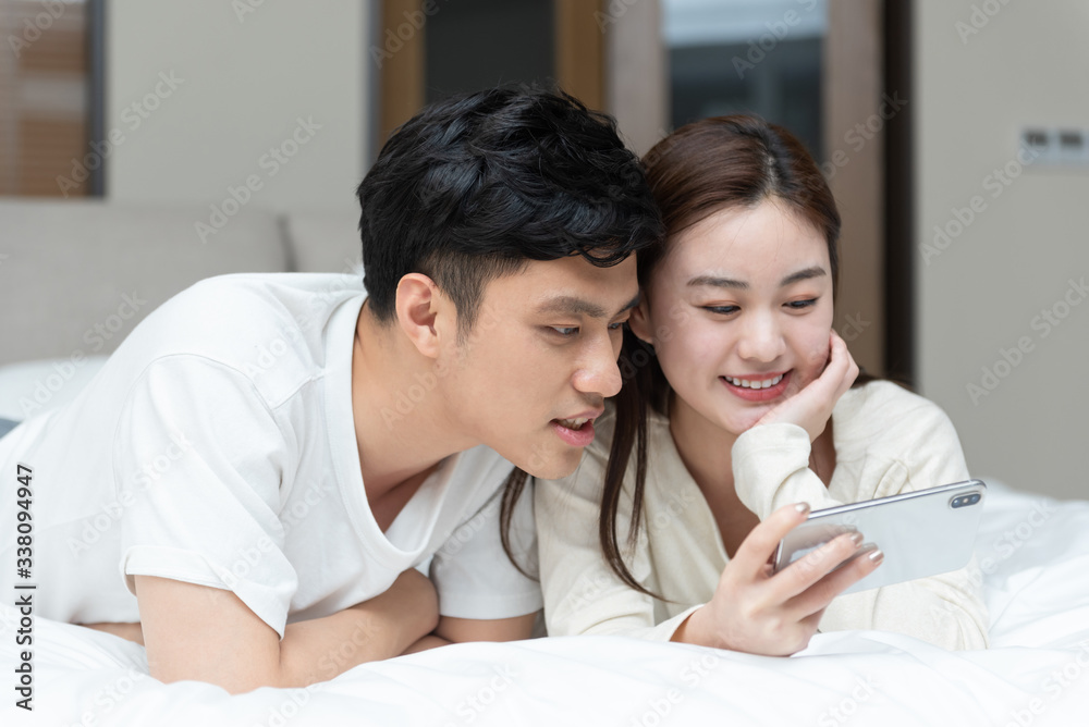 A young Asian couple is playing mobile phone in bed A young Asian couple is playing mobile phone in bed