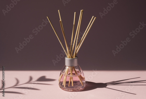 Fotografie Aromatic reed air freshener on pink background hard shadow