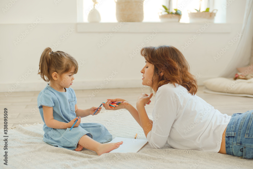 A young mother spends time with her little daughter at home.