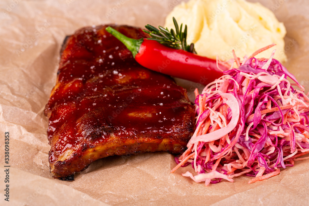 Pork ribs fried on a trochanter with sauce are served with puree potatoes and fresh cabbage salad
