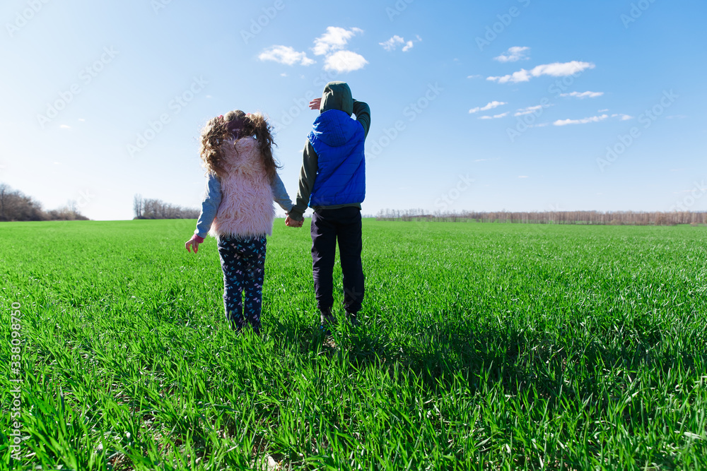 children stand on the field with green grass and hold hands