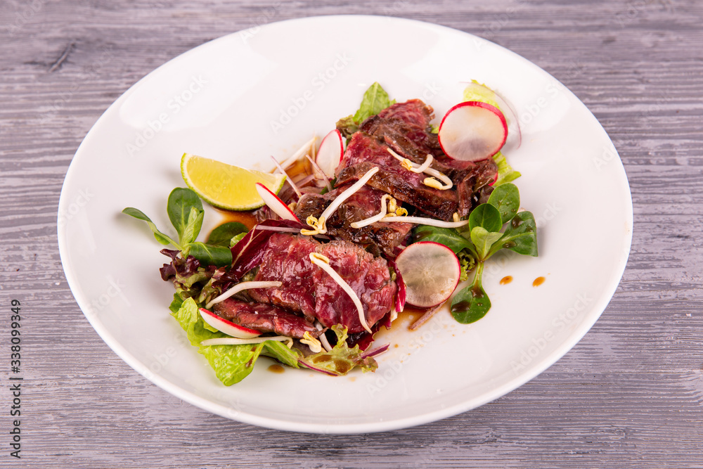Warm beef salad with terriaki sauce, served with radish, lime and fresh salad Warm beef salad with terriaki sauce, served with radish, lime and fresh salad