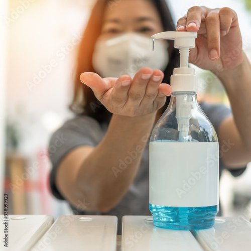 New normal for Covid-19 outbreak, coronavirus pandemic prevention with woman wearing n95 face mask cleaning hand using alcohol gel sanitizer during quarantine for hygiene antibacteria safety photo
