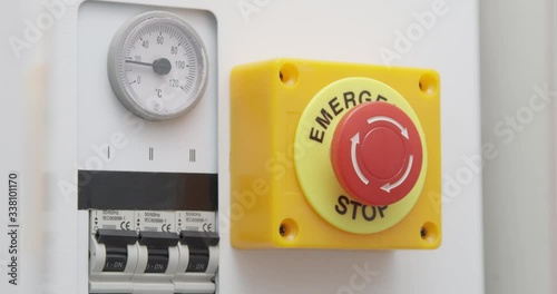Hand Pressing Emergency Stop Red Button on the Control System Panel with Electricity Switch
