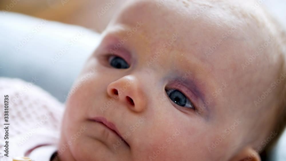 Serious pensive face of baby lying in bedding, looking away. Cute little girl at home. Closeup, high angle. Baby care concept Serious pensive face of baby lying in bedding, looking away. Cute little girl at home. Closeup, high angle. Baby care concept