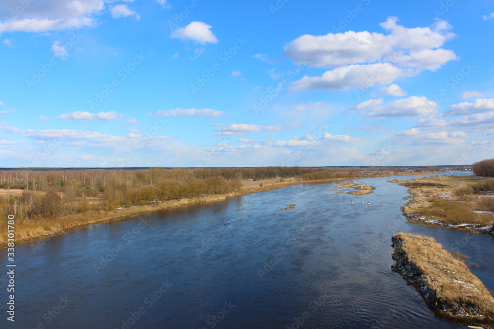 Beautiful landscape of nature from a height with a full-flowing river in the center, banks and a blue sky.