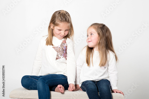 niñas felices sonrientes sentadas estudio fondo blanco