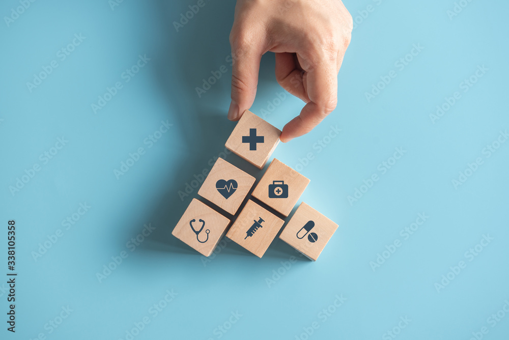 © oatawa - Health Insurance Concept, Hand of woman arranging wood cube stacking with icon healthcare medical on blue background, copy space.
