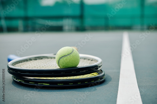 Two rackets and ball on outdoor tennis court at service line © DragonImages
