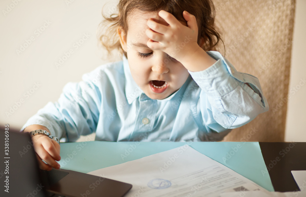 Workspace office desk with laptop. Little cute business girl sitting at table and looking on a important documents. Kid learning online. Workspace office desk with laptop. Little cute business girl sitting at table and looking on a important documents. Kid learning online.