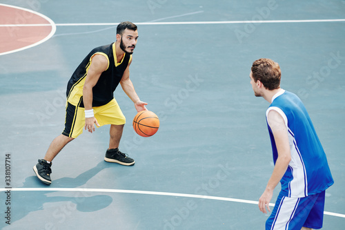 Quadro em tela Multi-ethnic young men playing basketball on outdoor court