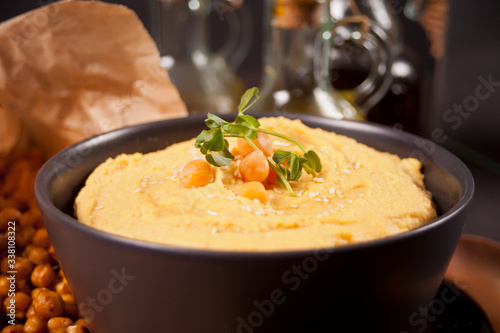 Traditional appetizer hummus with chickpea in a black bowl.