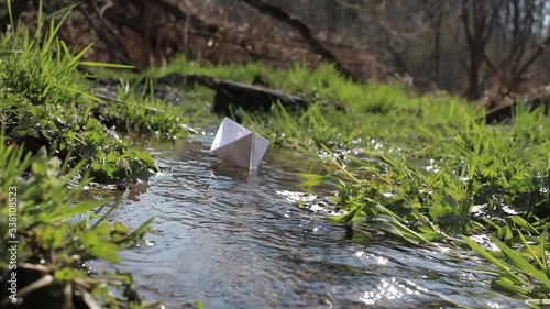 Paper ship. A paper boat is floating on the water. White paper ship. A boat  floats on water. A paper boat is floating on the river. Forest river. River runs along a forest.
