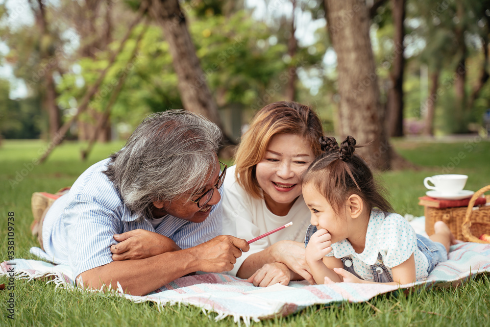 Grandmother,Grandfather and grand daughter enjoying sunny garden holiday together, outdoors space, leisure lifestyle,happy teaching with flare light sky in park. Grandmother,Grandfather and grand daughter enjoying sunny garden holiday together, outdoors space, leisure lifestyle,happy teaching with flare light sky in park.