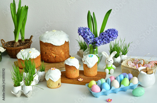 Easter orthodox sweet bread, multicolored eggs with green grass.Easter greeting card template. Homemade pasques.Easter sweets on light background.Holidays breakfast concept with copy space photo