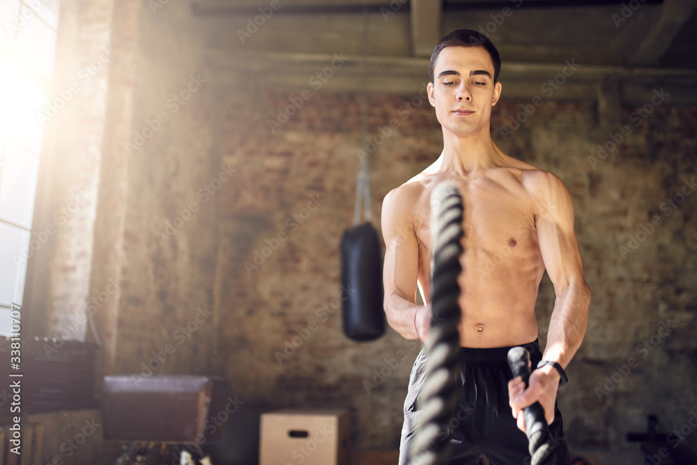 Sportsman with ropes against background of brick wall in gym Sportsman with ropes against background of brick wall in gym
