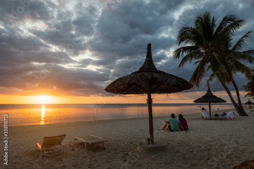 Couple watching sunset on the beach at Flic en Flac, Mauritius