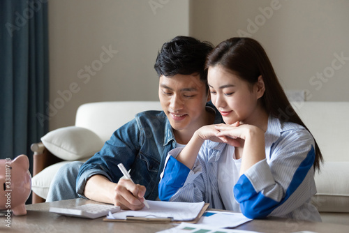 A young asian couple is sitting on the carpet planning