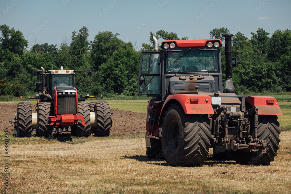two red tractors with large wheels in the field during tests during the exhibition two red tractors with large wheels in the field during tests during the exhibition