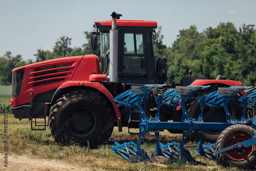 Obraz premium red tractor with large wheels in the field during tests during the exhibition