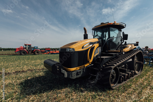 yellow caterpillar tractor in summer in a field during a test drive for plowing a land