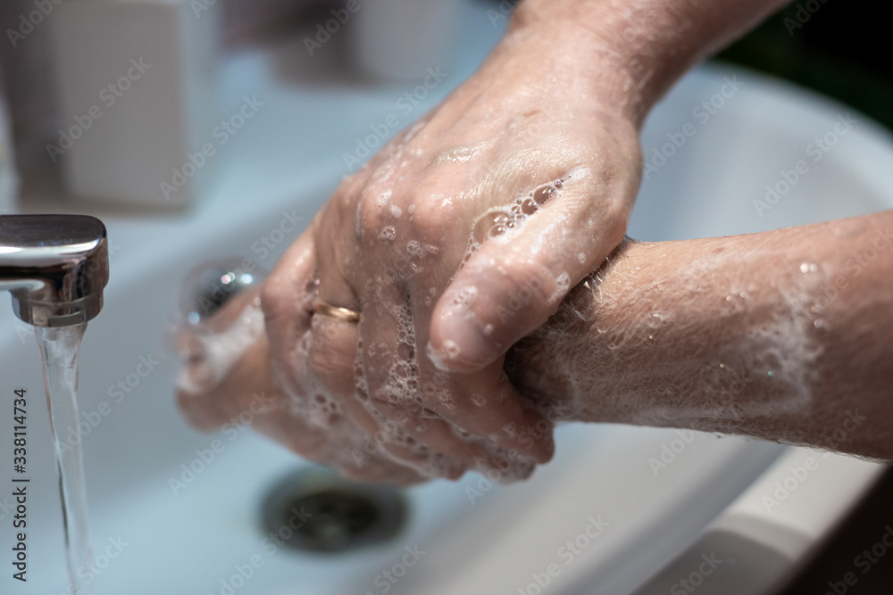 Fototapeta premium man washes his hands with liquid soap over a sink at home