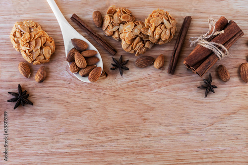 Almond cookies, bunch of cinnamon and almonds with star anise star anise, white wooden spoon, on a light brown wooden board. Great background for a cafe or restaurant menu, signboard