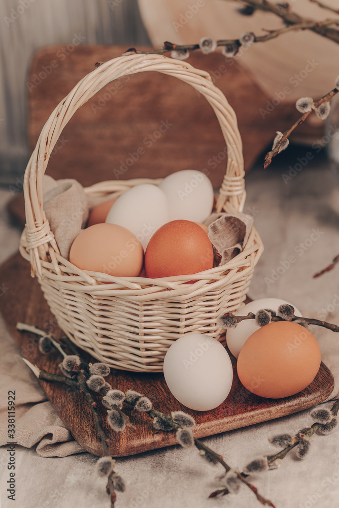 Easter eggs in basket and willow branches on rustic background Easter eggs in basket and willow branches on rustic background