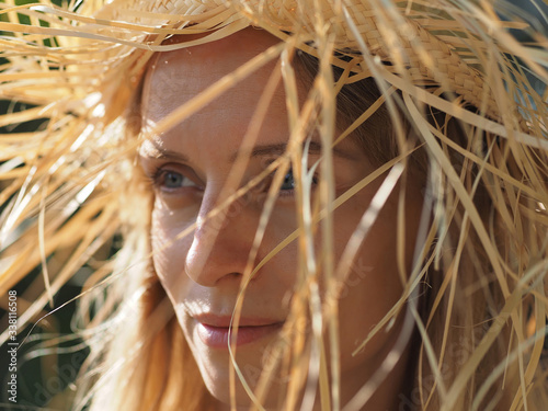 Close up shot. Portrait of beautiful woman in hat enjoying sunset golden light in summer meadow. Selective focus.