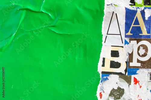 Torn crumpled and peeling green paper placard poster on colorful collage from clippings with letters and numbers texture background. Copy space for text message.