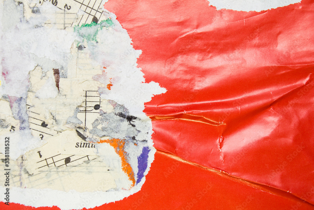 Torn and crumpled glossy red poster on old scraps of paper music sheet with notes background.