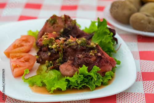 Boiled octopus with salad and tomatoes and mojo sauce. Traditional canary potatoes on background. Tasty cousine in Garachico.