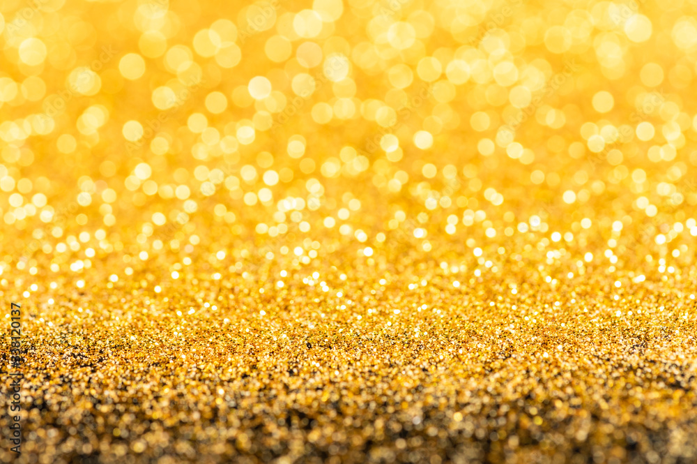 Gold glitter texture. Sparkling gold bright bokeh from blurred diamond dust on black background. Abstract golden bokeh background. Selective focused