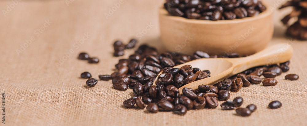 Close up roasted coffee beans on sackcloth with wooden bowl and tea spoon Close up roasted coffee beans on sackcloth with wooden bowl and tea spoon