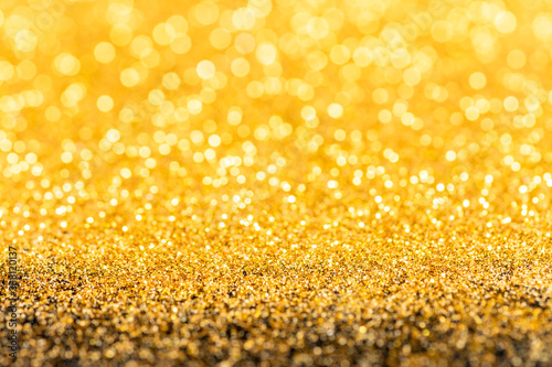 Gold glitter texture. Sparkling gold bright bokeh from blurred diamond dust on black background. Abstract golden bokeh background. Selective focused