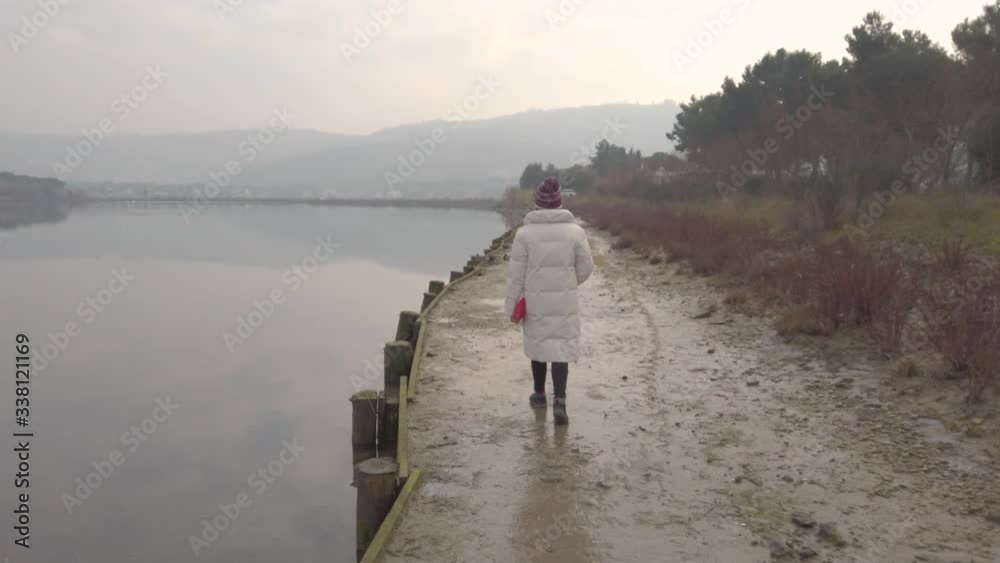 A girl strolling on the shore of a lake. A girl strolling on the shore of a lake.