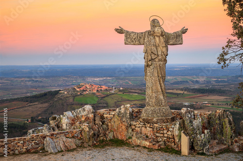 View of the Serra da Marofa viewpoint, in Portugal, at sunset, with Cristo Rei in the foreground and the historic village of Castelo Rodrigo in the background. photo