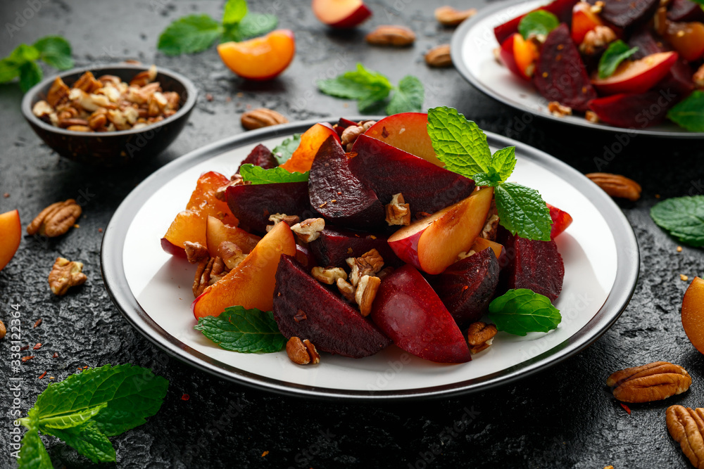 Vegan Plum, beet salad with pecan nuts, mint and herbs on rustic black table Vegan Plum, beet salad with pecan nuts, mint and herbs on rustic black table