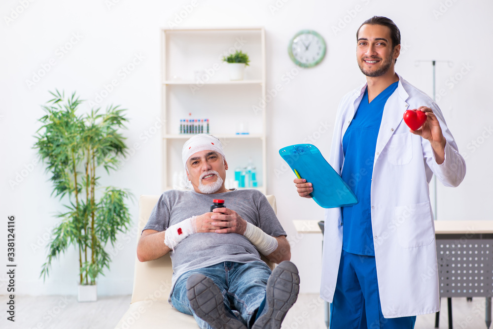 Fototapeta premium Young male doctor and old patient in first aid concept