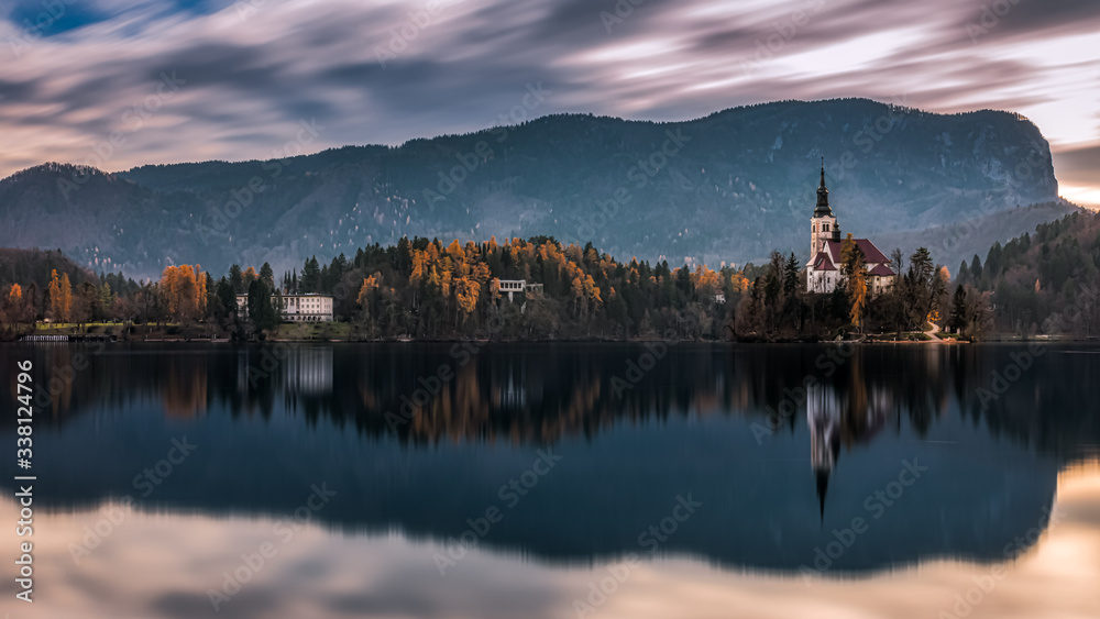 Cloudy backlit shot of of the central island with the famous church on it and the surrounding autumnal landscape at the Lake Bled, Slovenia