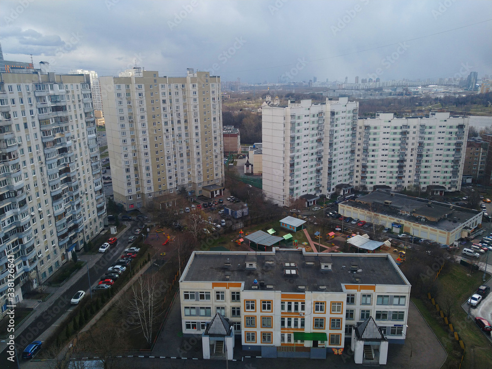 White multi-storey residential panel building shot from a height against the background of a city landscape with a distant horizon with a dark sky in cloudy weather White multi-storey residential panel building shot from a height against the background of a city landscape with a distant horizon with a dark sky in cloudy weather