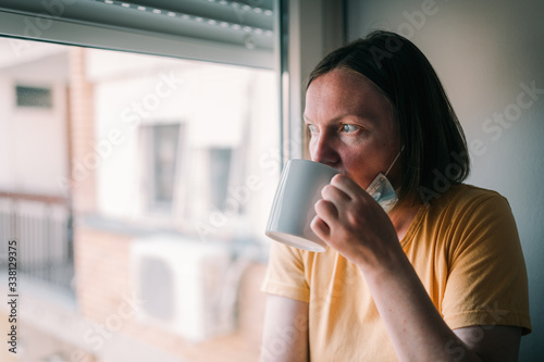 Woman in self-isolation during virus outbreak drinking coffee