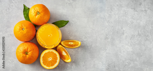 Top view of fresh orange juice, oranges and slices on grey concrete background © Katecat