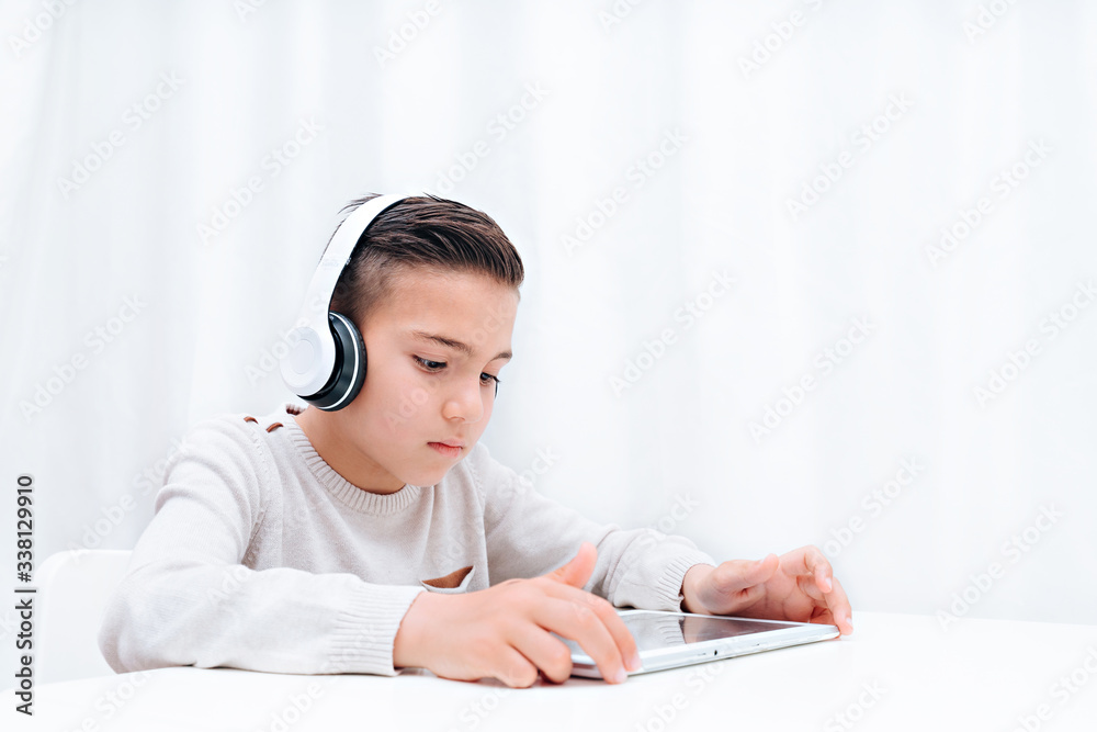 Child study online sitting with tablet and headphones. Child listening to teacher and looking on tablet Child study online sitting with tablet and headphones. Child listening to teacher and looking on tablet