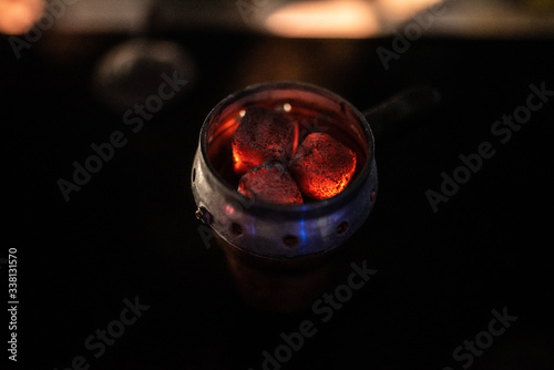 hot red coals with hookah sparks in metal bowl for Shisha Smoking Coal for hookah close-up  hot red coals for hookah in Cup close up photo