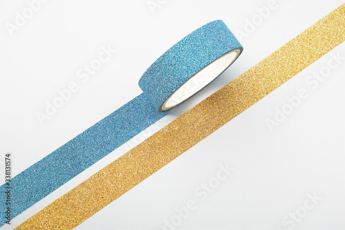 Two rolls of glitter tape and parallel strips on white background