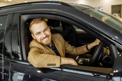 happy caucasian guy made purchase in dealership, he is happy to get a new car. business class car, vehicle, transport, automobile, car concept